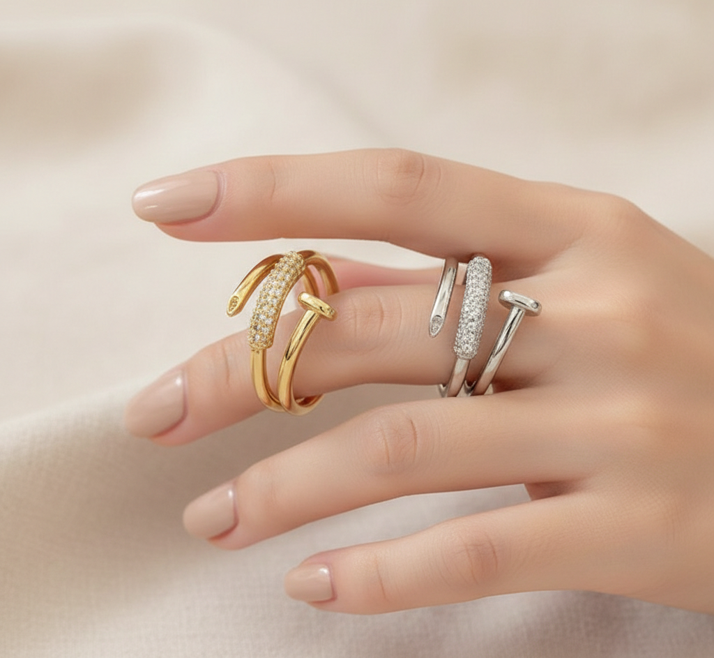 Hand wearing two gold and silver rings on a neutral background